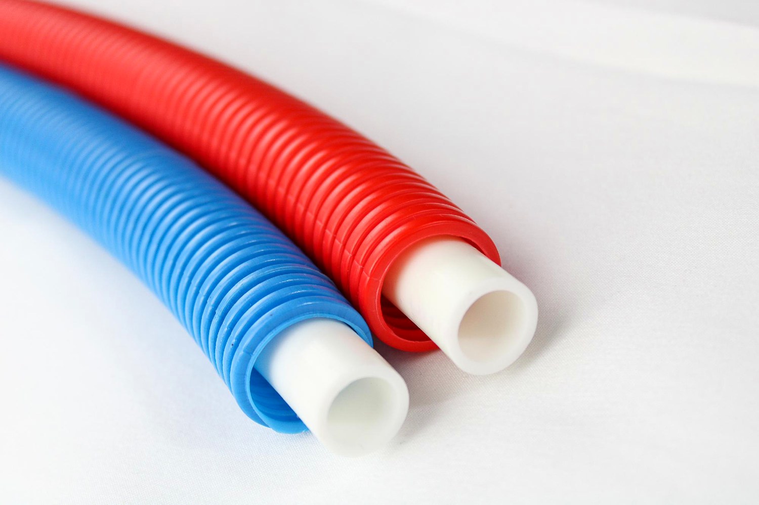 Cut ends of red and blue Livoplast pipe, showing the white PE-RT inner pipe inside each corrugated sleeve.